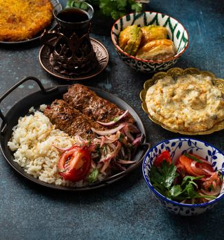 Traditional Turkish food, assorted dishes and mezze appetizers on rustic background from above. Pide, Lahmacun, meat kebab, Turkish meatballs, sweet baklava and Kunefe. Middle East cuisine, top view