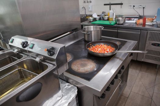 Frying pan with vegetable mix cooking on the stove at restaurant kitchen, copy space