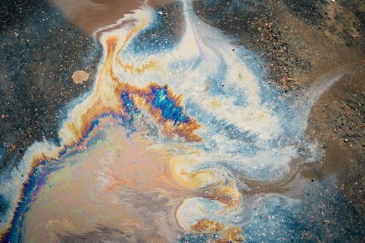 Dirty multi-colored stain from engine oil on asphalt. Environmental pollution concept.