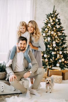 Happy family: mom, dad and pet. Family in a bright New Year's interior with a Christmas tree.