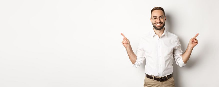 Confident bearded man smiling, pointing left and right at copy spaces, standing over white background.