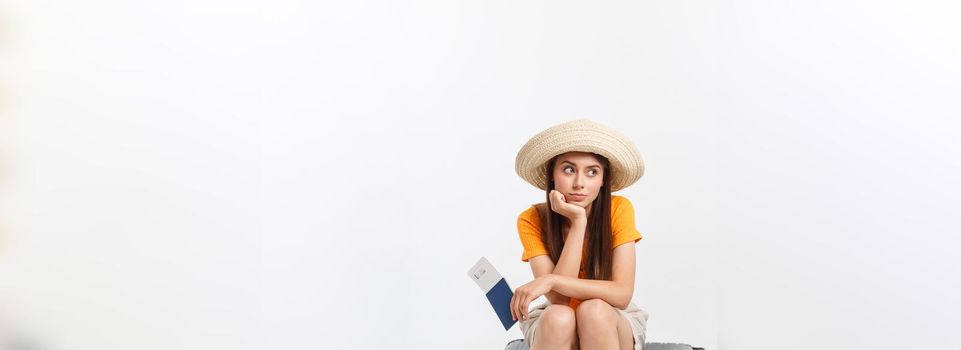 Lifestyle and travel Concept: Young beautiful caucasian woman is sitting on suitecase and waiting for her flight.Isolated over white background.