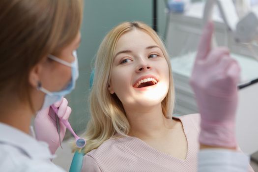 Cheerful young woman smiling during dental checkup by professional dentist