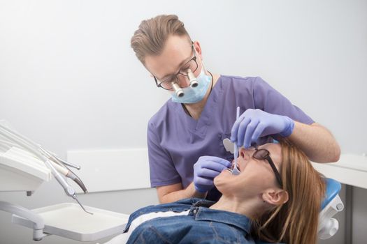 Professional dentist wearing microscope glasses, working at his dental clinic, copy space