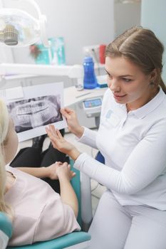 Vertical shot of a female dentist showing jaw x-ray scan to her patient