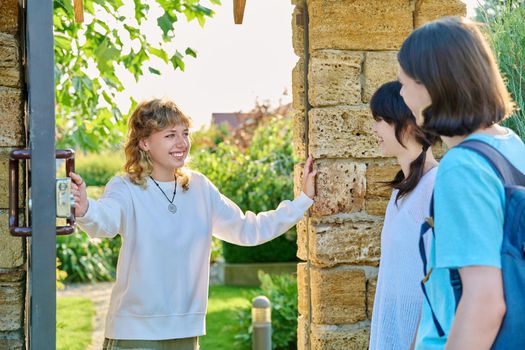 Meeting of friends, a young female with a guy and a girl near the front door to the yard. Welcome, youth, friendship, students, lifestyle concept