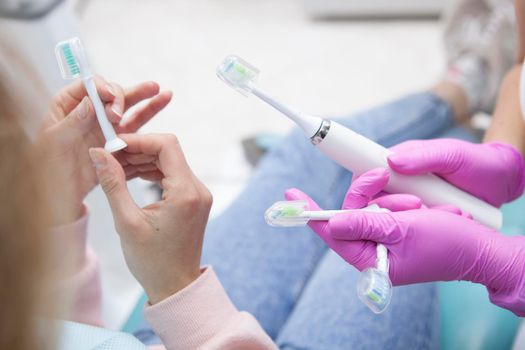 Unrecognizable woman examining replacement heads for electric toothbrush at dentist office