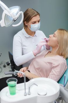 Vertical shot of a professional dentist examining teeth of young woman