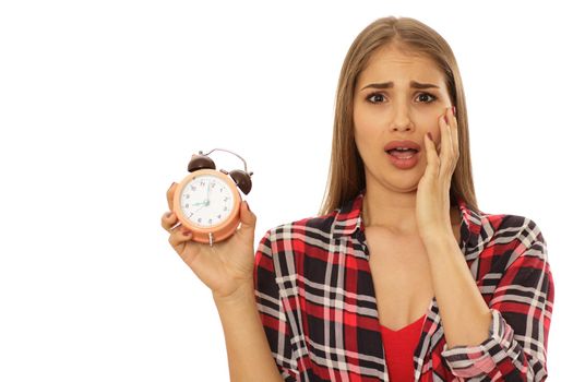 Young woman looking terrified screaming with her hand to her face holding alarm clock isolated on white copy space. Time management, timing, being late concept. Beautiful woman looking shocked