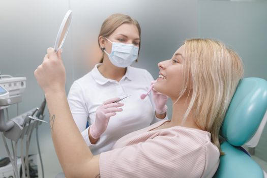 Happy woman smiling looking in the mirror after dental checkup