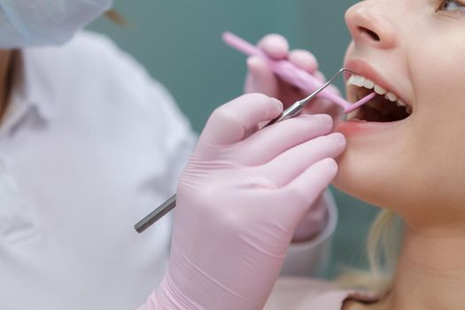 Cropped close up of a woman having her teeth examined and cured by professional dentist