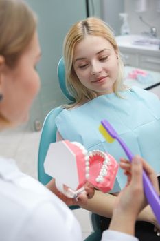Vertical shot of a female patient sitting in dental chair talking to her dentist