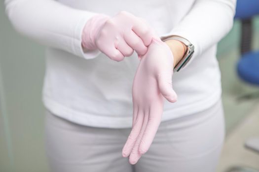 Cropped shot of female doctor putting on rubber gloves before surgery