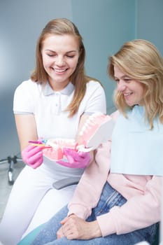 Vertical shot of a cheerful female dentist and her mature patient discussing interdental toothbrushes