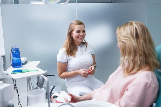 Lovely young female dentist talking to patient at her dental office