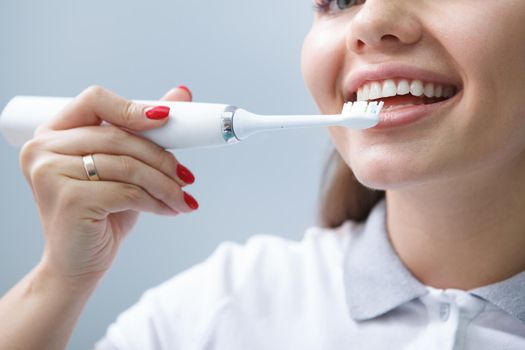 Cropped close up of a female dentist showing correct teeth brushing with electric toothbrush