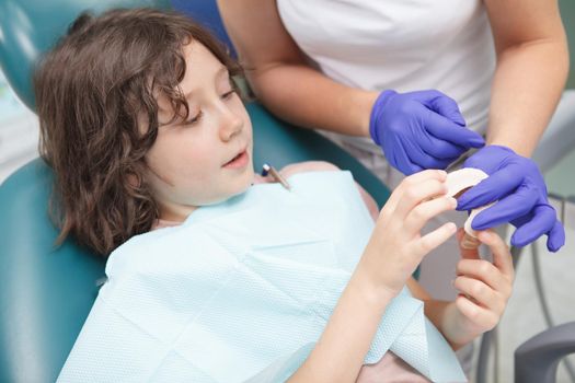 Charming young boy talking to his dentist during dental appointment