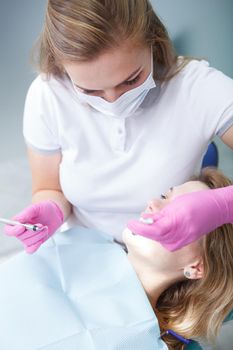 Vertical cropped shot of a female dentist checking teeth of female patient