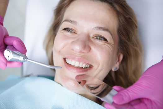Close up of a cheerful mature woman smiling while dentist examining her teeth