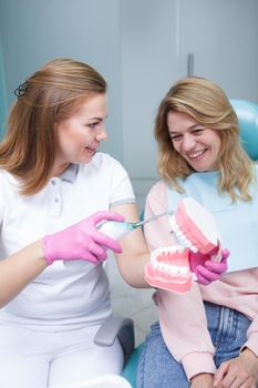 Vertical shot of a mature female patient learning how to use ultrasonic toothbrush from her dentist