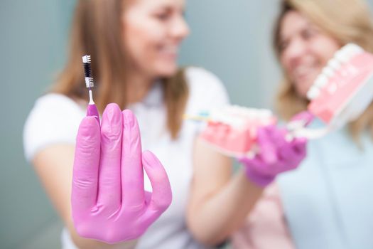 Selective focus on interdental toothbrush in hands of female dentist
