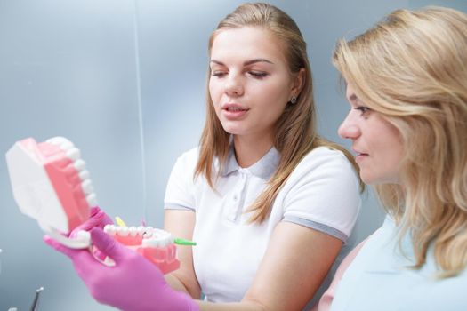 Lovely female dentist educating her mature patient on using interdental brushes