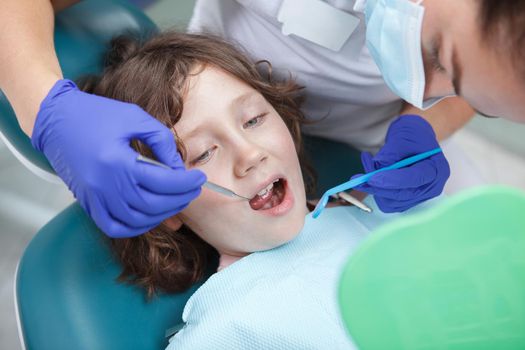 Close up of a dentist examining teeth of cute young boy