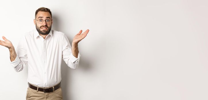 Clueless worried manager shrugging, looking confused, standing over white background.