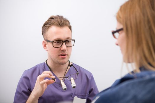 Young male dentist talking to his female patient