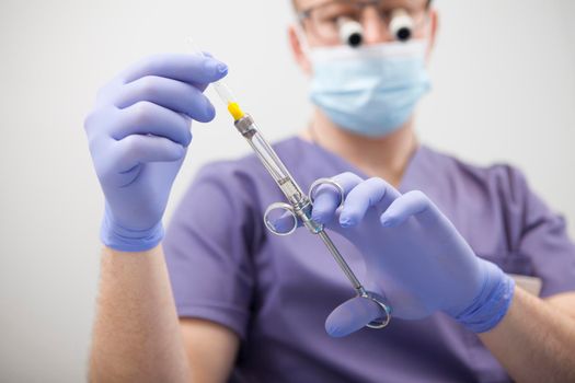 Close up of anesthesia syringe in hands of male doctor wearing microscope glasses, copy space