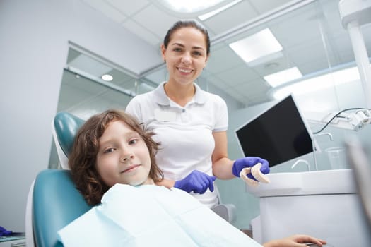 Happy young boy and cheerful female dentist smiling to the camera