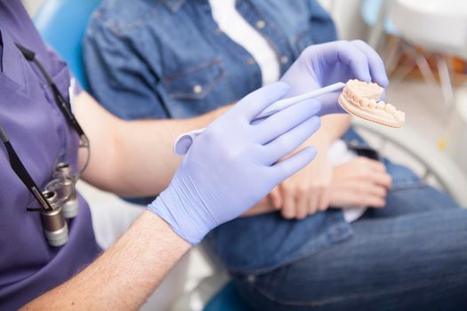 Unrecognizable dentist showing dental mold to the patient