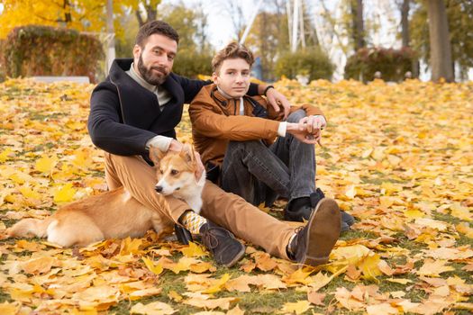 Father and son with a pet on a walk in the autumn park.