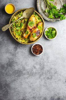 Biryani chicken, traditional dish of Indian cuisine, with basmati rice, fried onion, fresh cilantro in bowl on gray rustic stone background. Authentic Indian meal, top view, close-up, space for text