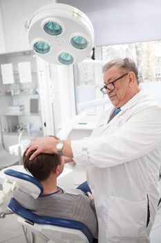 Vertical shot of a senior doctor examining lymphatic nods of a patient before dental treatment