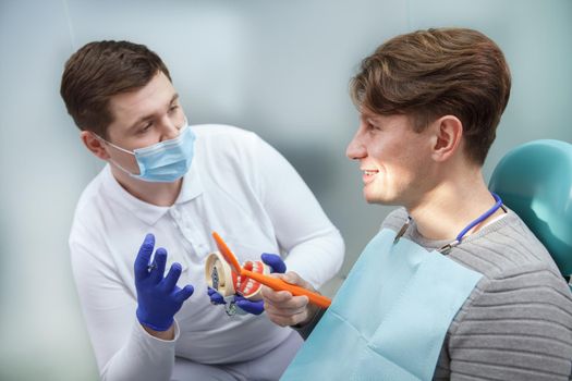 Young male dentist wearing medical face mask, talking to his patient