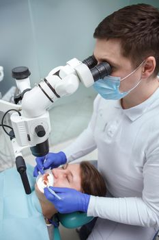 Vertical top view shot of a male dentist looking into dental microscope while working