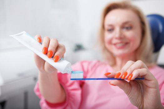 Selective focus on toothpaste woman is squeezing on a toothbrush