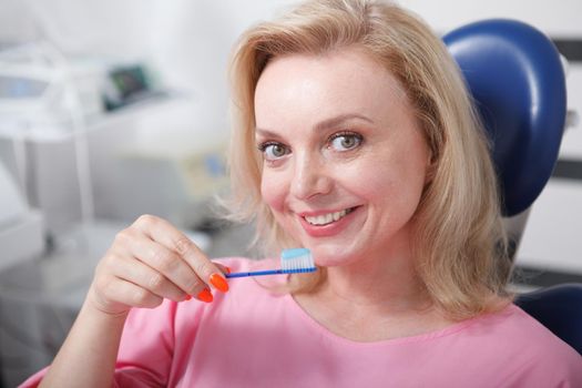 Cheerful woman smiling, holding toothbrush with toothpaste