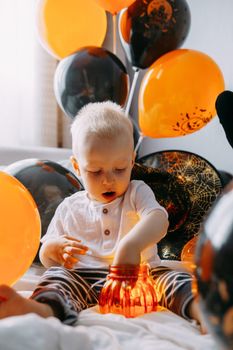 Children's Halloween - a boy in a carnival costume with orange and black balloons at home. Ready to celebrate Halloween