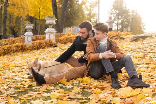 Father and son with a pet on a walk in the autumn park.