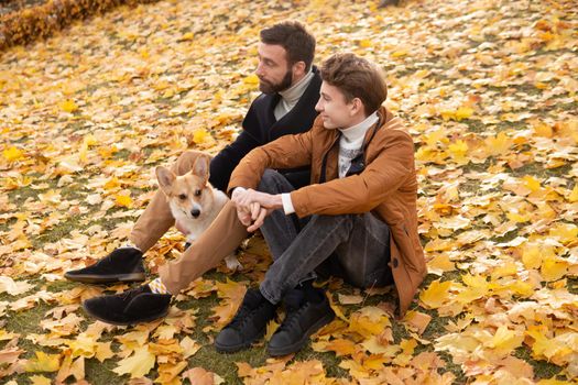 Father and son with a pet on a walk in the autumn park.