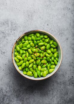 Fresh ripe green edamame beans without pods in bowl on gray stone background. Top view, close up. Light and healthy asian snack good source of vegetarian protein for diet and nutrition