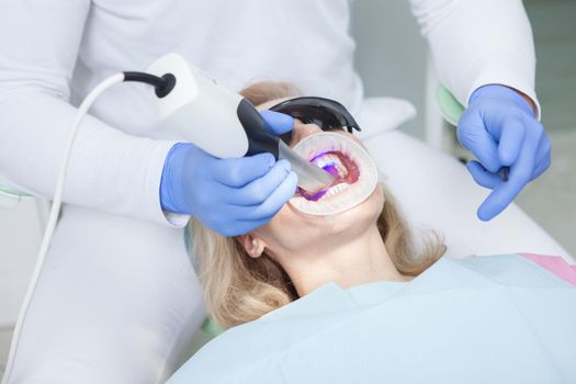 Female patient having her teeth scanned by professional dentist
