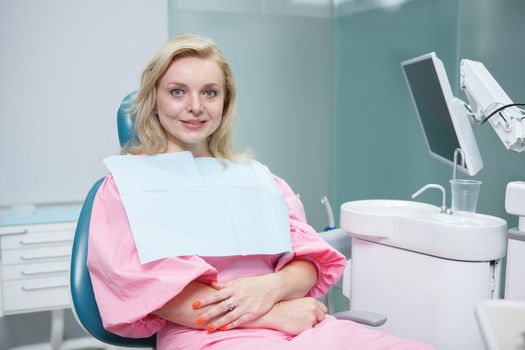 Charming mature woman sitting in dental chair, smiling to the camera