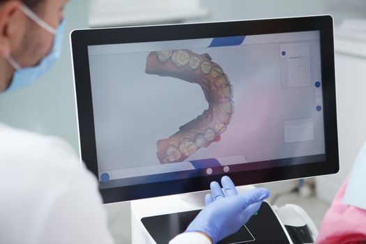 Cropped close up of a dentist examining teeth scan on the computer