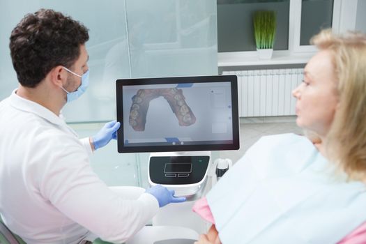 Dentist and patient looking at dental scan on the screen of computer