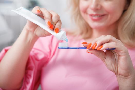 Unrecognizable woman squeezing toothpaste on her toothbrush