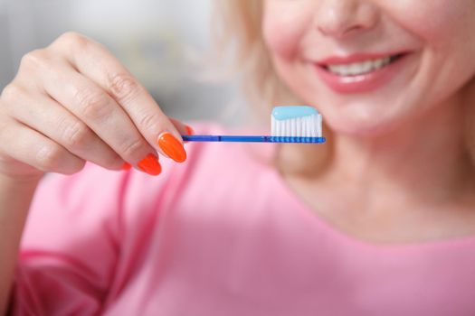 Selective focus on a toothbrush with toothpaste unrecognizable woman is holding