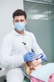 Vertical shot of a professional dentist wearing medical face mask, working with patient